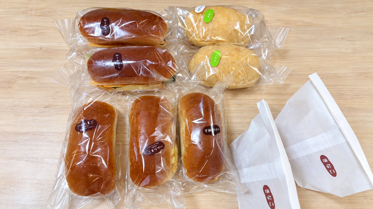 木のテーブルに並べた袋入りのコッペパンと揚げパン