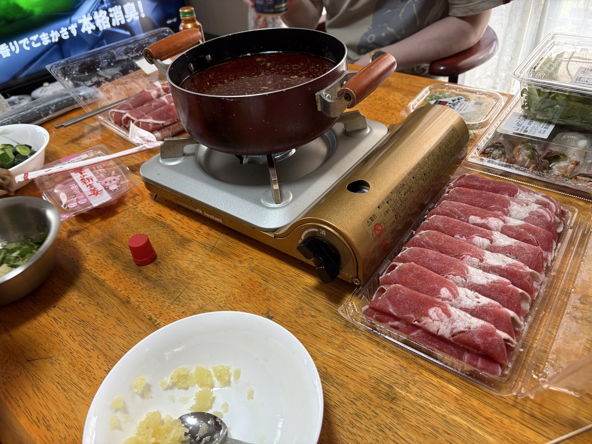 火鍋と肉や野菜が並ぶ食卓