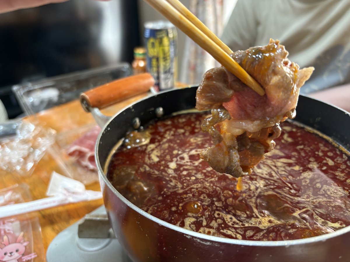 箸で火鍋の肉を持ち上げた様子