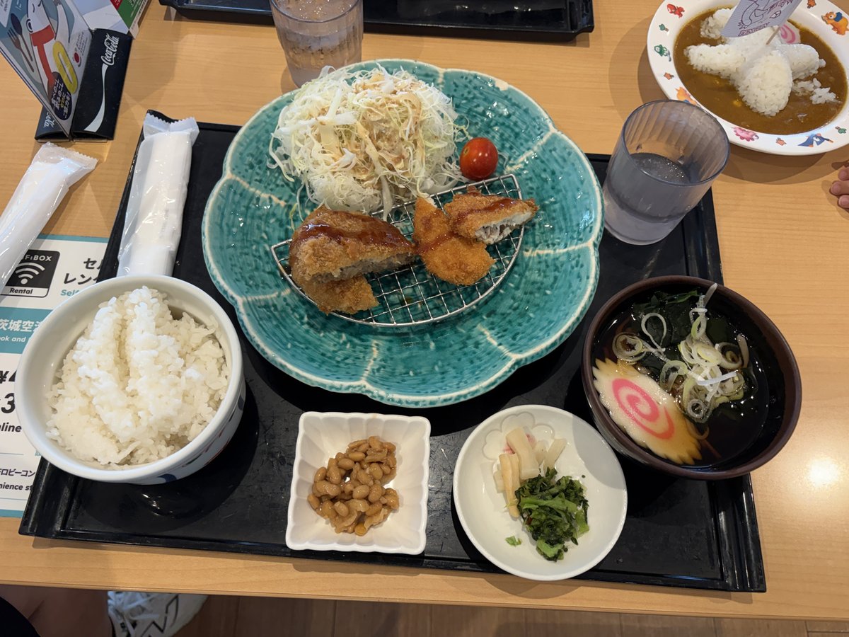 すぎのや本陣の「ようこそ茨城定食」。メンチカツとチキンカツ、千切りキャベツ、ご飯、納豆、漬物、そばが黒いトレーに並ぶ