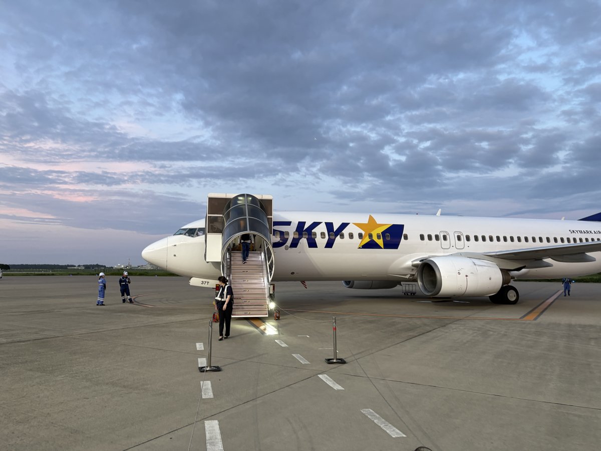 夕暮れの茨城空港のエプロンに駐機するスカイマークの機体。タラップから乗客が搭乗している