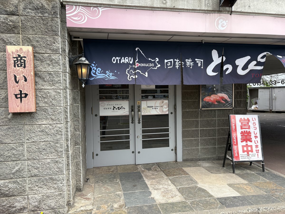 「回転寿司とっぴ〜」の紺色の暖簾と、営業中の看板が出た店舗入口